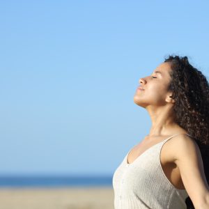 Side view portrait of a relaxed latin girl breathing deeply fresh air on the beach a sunny day